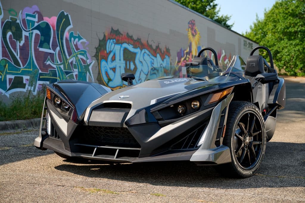 Grey Polaris Slingshot beside a graffiti wall