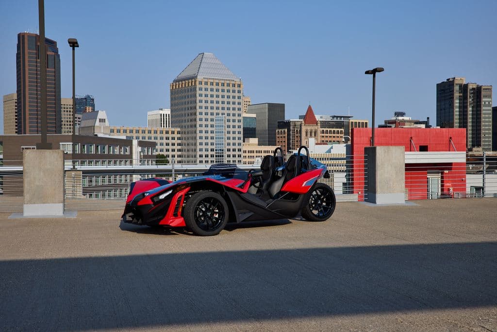 Red Polaris Slingshot parked against a city skyline